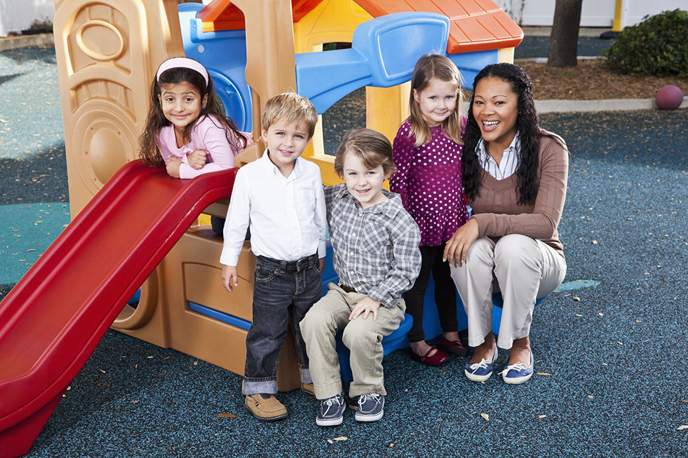 Teacher (20s) with preschoolers on playground (3-4 years).